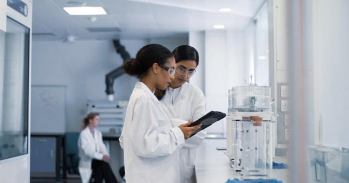 Two women reviewing a tablet in a lab.